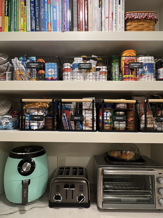 Organized pantry shelves with labeled snack baskets and small kitchen appliances